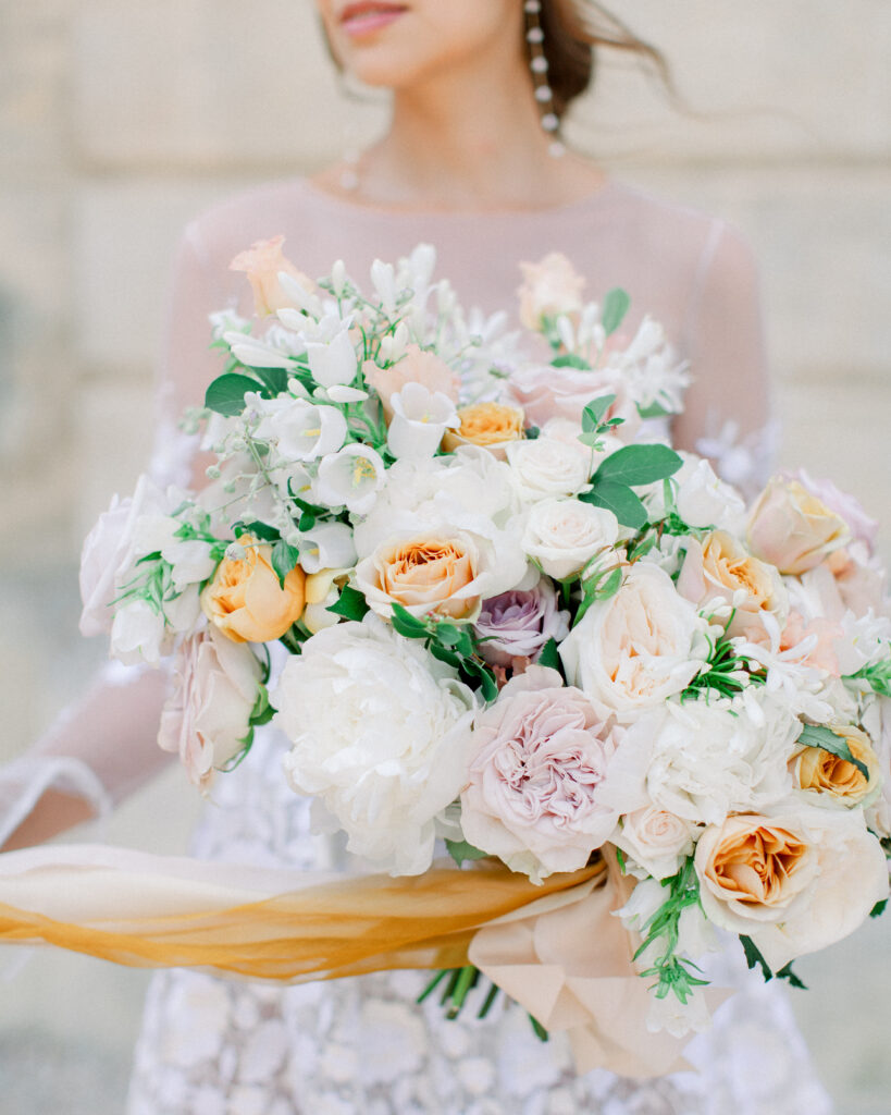 large wedding bouquet of ivory, gold, and purple at french chateau wedding venue