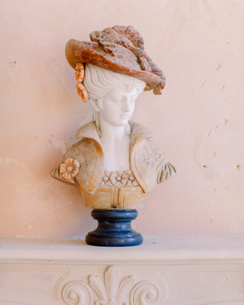 Ornate bust of a woman in 18th century attire on a mantlepiece inside a french chateau wedding venue