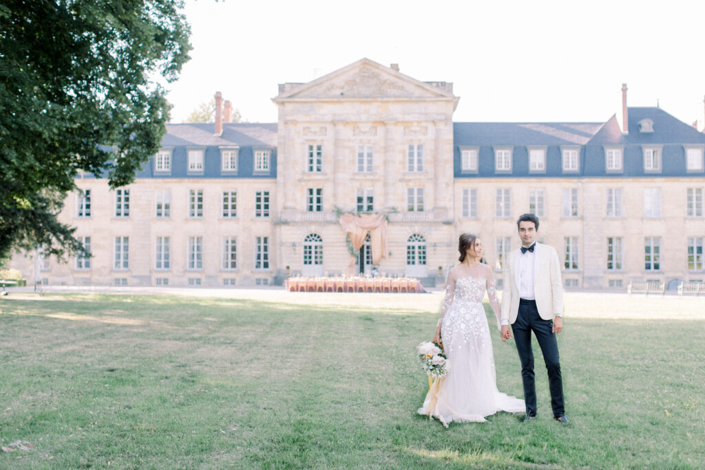 couple standing hand in hand in front of 18th century french chateau wedding venue