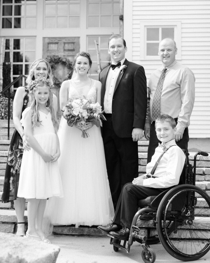 black and white photo of weddding couple with family, in front of steps to a wedding venue