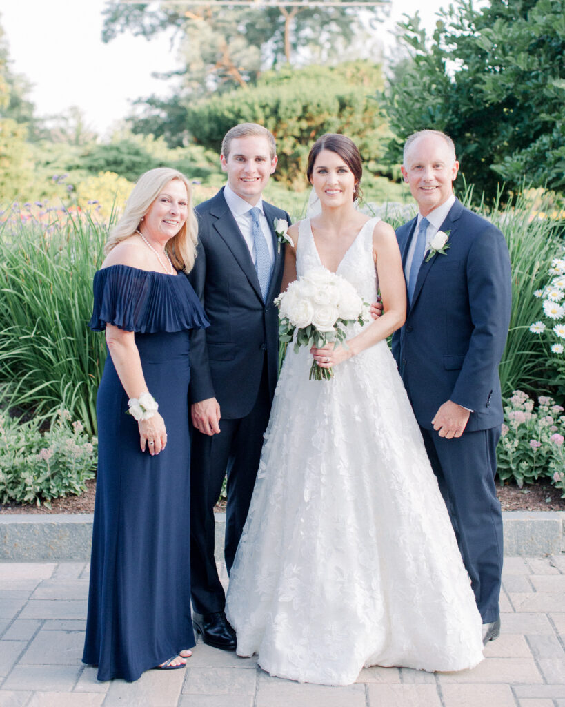 wedding couple standing with their parents, men in blue suits and mother in a navy blue floor length gown