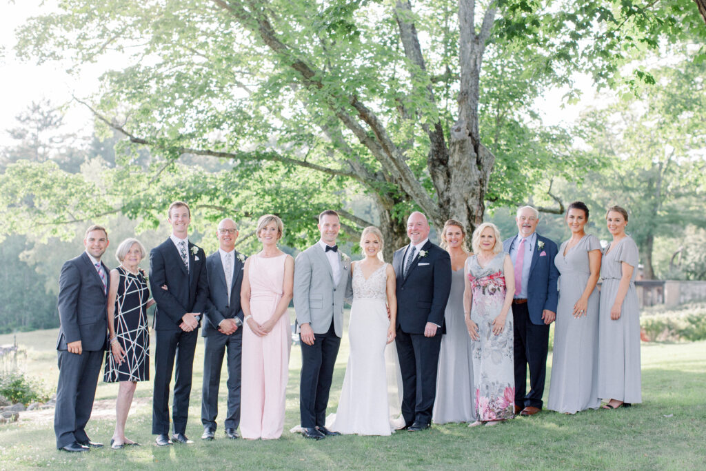 large family with wedding couple on a lush green lawn in front of a garden wedding venue, wedding family photos