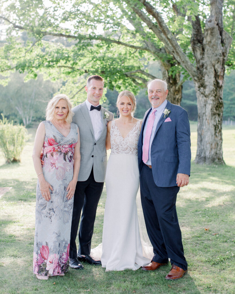 wedding couple with parents in lush green lawn