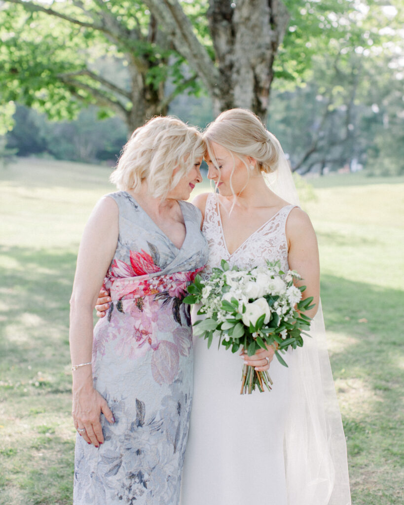 bride holding bouquet, embracing mother in a hug, wedding family photos